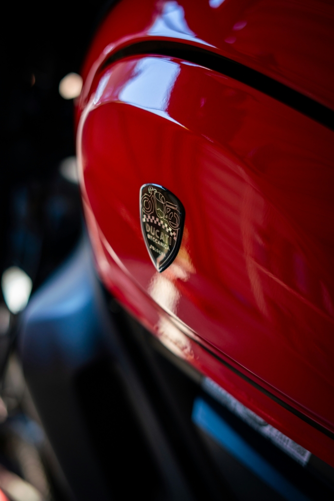 Close-up of a glossy red motorcycle body with a Ducati logo badge on the panel